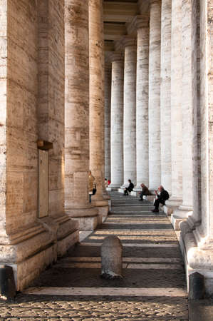 people in the background are sitting in the same way, and they seem to enjoy the beautiful sunny day in the shadow of the columnsのeditorial素材