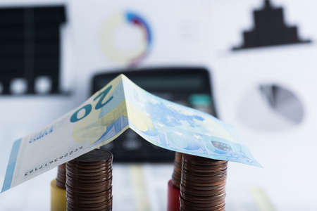 house made of coins and banknote. In the background calculationsの写真素材