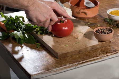 Chop celery, tomato, onions on a wooden cutting board for cooking.の写真素材