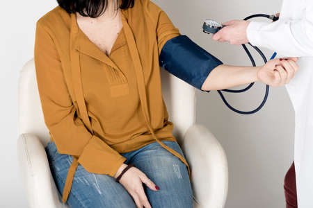 Doctor measures the blood pressure of a patient woman.