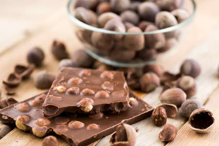 Delicious milk chocolate with hazelnuts on a wooden table.
