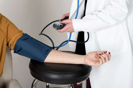 Doctor measures the blood pressure of a patient woman.