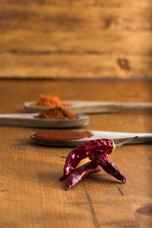 red chili pepper , some whole, some ground, some chopped and some homemade sauce on wooden tableの写真素材