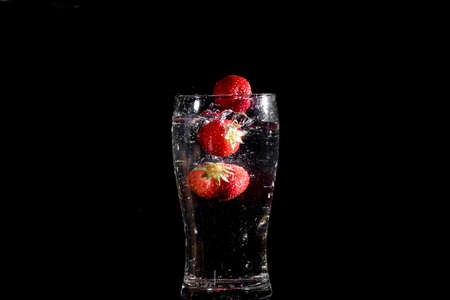 Strawberries that are about to fall into glass waterの写真素材