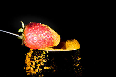 Splash of turmeric , caused by a fall of a strawberry on a spoonの写真素材