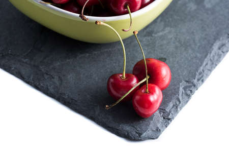 red cherries cutlery on dark stone and in the background a bowl with cherries .の写真素材