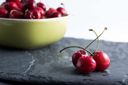 red cherries cutlery on dark stone background cherries in a bowl.の写真素材