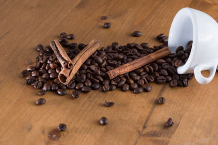 small cup reversed with coffee beans scattered on the wooden tableの写真素材