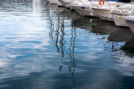 boats lined up at the harbor with reflections on waterの写真素材