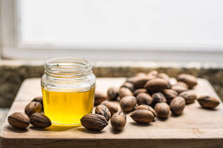 Walnut oil in a jar, some delicious nuts are on a wooden table