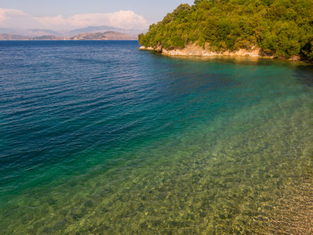 Tranquil turquoise waters meet a lush green shore.の写真素材