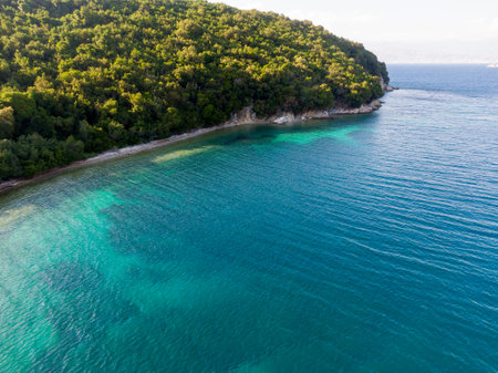 Tranquil turquoise bay meets lush green hillside in serene aerial view.の写真素材