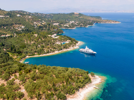 Luxury yacht anchored in a serene turquoise bay, surrounded by lush greenery.
