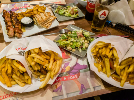 Table with various fast food dishes, including gyros, salads, and fries.の写真素材