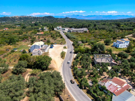 Aerial view of a rural road, buildings, and landscape with mountains in the background.の写真素材
