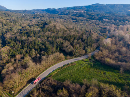 Aerial view of a truck on a winding road through a forest.