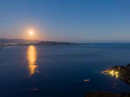 Moonlit Bay: Serene night scene with moon reflecting on calm water.の写真素材