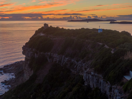 Sunset over coastal cliffs and ocean. Serene landscape with a small structure atop the cliffs.の写真素材