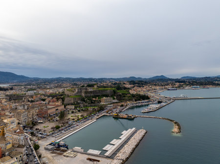 Coastal city harbor with fortress and marina. Boats, buildings, and mountains in the background.の写真素材