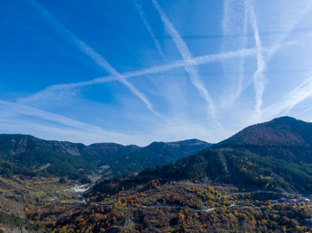 Mountain valley landscape under a vibrant blue sky with contrails.の写真素材