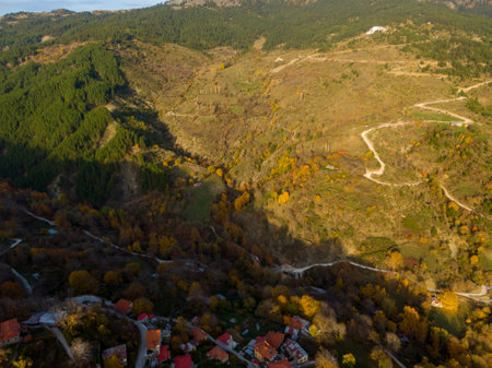 Autumnal mountain village aerial view. Winding roads, colorful foliage, and rustic houses.の写真素材