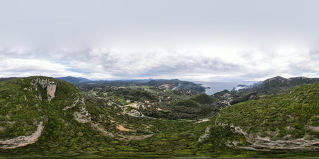 Panoramic view of a lush green valley meeting the sea under a cloudy sky.