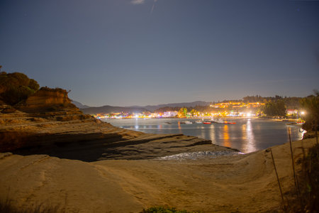 Night view of coastal town lights reflected on calm water.の写真素材