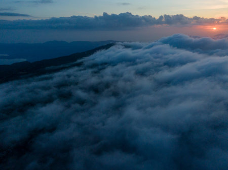 Sunset over a sea of clouds, mountains in the distance.の写真素材