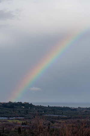 A vibrant rainbow arches over a tranquil landscape, a breathtaking scene of nature's beauty.の写真素材