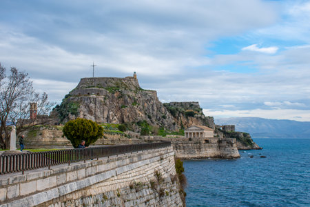 Scenic coastal view with historic fortress and temple under a cloudy sky.の写真素材