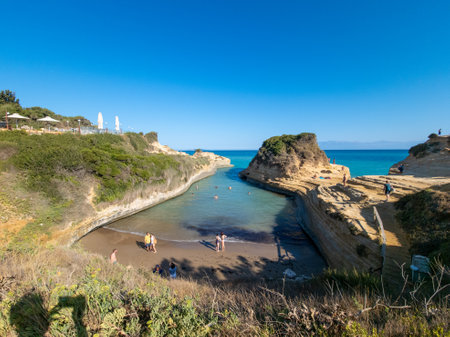 Picturesque cove with clear turquoise water, rock formations, and beachgoers enjoying the summer...