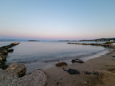 A serene coastal scene shows a calm bay, sandy beach and a tranquil atmosphere at dusk.の写真素材