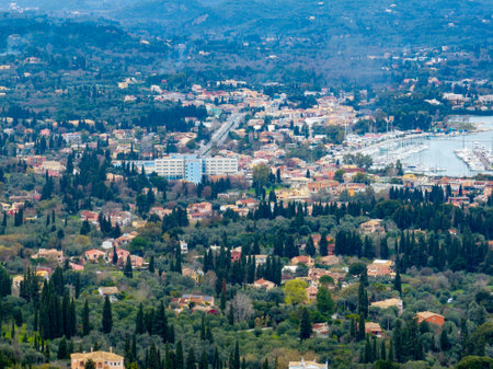 Elevated view captures a European town nestled among green hillsides and a harbor filled with boats.の写真素材