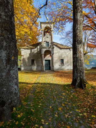 Autumn's embrace on a historic stone building, framed by trees in vibrant fall foliage.の写真素材
