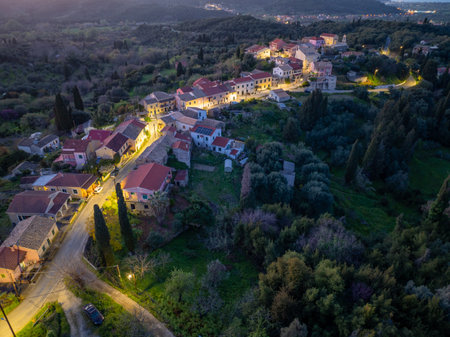 Picturesque European village nestled amongst lush trees, illuminated by soft lights in twilight.の写真素材
