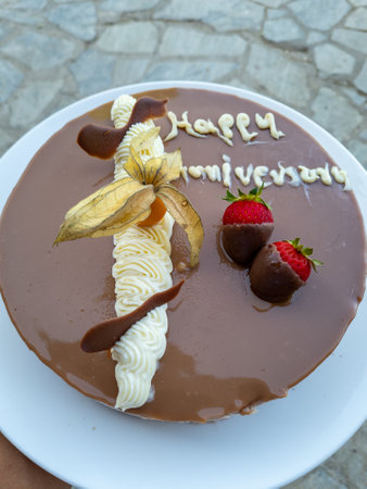 Close-up of an anniversary cake decorated with chocolate dipped strawberries.
