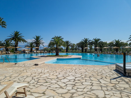 Expansive resort swimming pool surrounded by palm trees, offering a luxurious vacation getaway.の写真素材