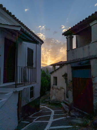Picturesque European village street at sunset, charming old buildings line the pathway with a mountain view.の写真素材