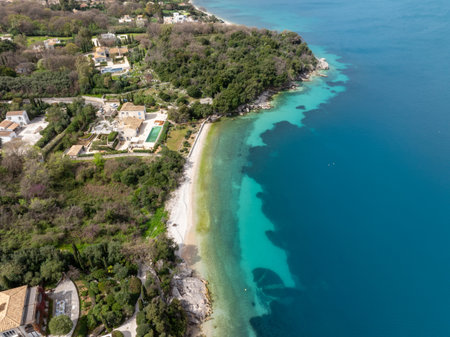 Aerial view showcases luxurious homes nestled amidst lush greenery along a stunning coastline.の写真素材