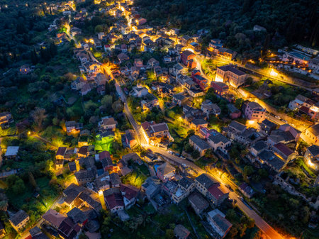 Aerial view of a charming European town nestled among lush greenery, illuminated by warm streetlights.の写真素材