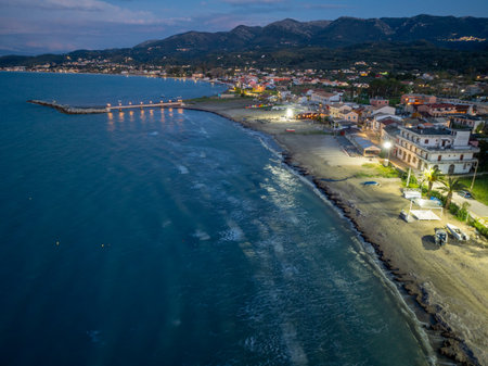 Coastal village nestled between the tranquil sea and majestic mountains, bathed in soft twilight.の写真素材
