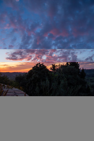 A dramatic sky filled with textured, colorful clouds at sunset, casting a warm glow over the landscape.の写真素材