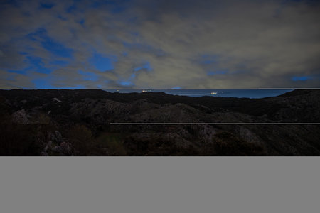 Dramatic landscape at dusk: rolling hills meet the horizon under a sky ablaze with twilight hues.