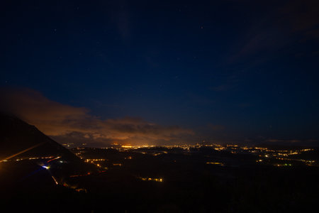 Night view showcases the landscape, with scattered lights and a starry sky illuminating the sceneの写真素材