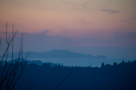 Twilight view of silhouetted hills and trees against a gradient sky, capturing the fading light.の写真素材