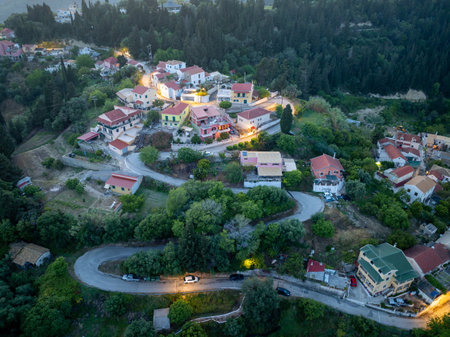 Aerial view of a quaint village nestled in a lush, green landscape with winding roads and charming houses.の写真素材