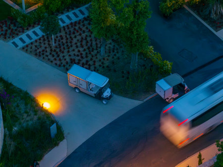 Aerial night scene featuring electric service vehicles in a landscaped setting with trees and gardens.の写真素材