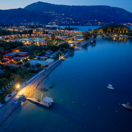Aerial view of a coastal resort at dusk, lights illuminating the buildings and tranquil shoreline.の写真素材