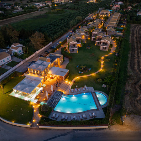 Aerial view of a tranquil resort complex illuminated at dusk, featuring a swimming pool and housing.の写真素材