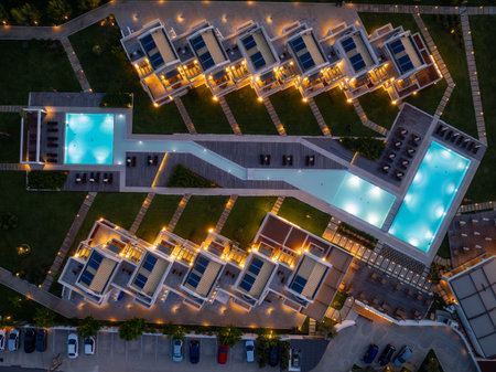Aerial view of modern resort with swimming pools, villas, landscaping, and nighttime lighting.の写真素材